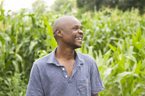Moses Momanyi, co-owner of Dawn2Dusk Farms and co-founder of the Kilimo Minnesota farm incubator program, stands in front of a row of heirloom corn near Cambridge, Minnesota. Portrait of Moses Momanyi