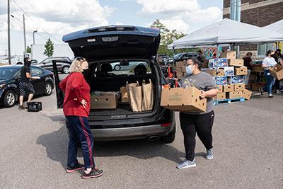 Two people load boxes into trunk during food distribution