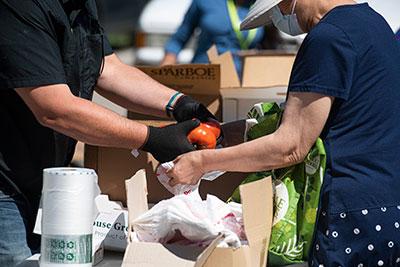 Two people load produce into a box of food