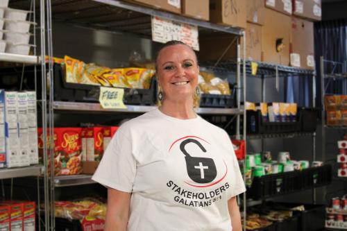 Volunteer Coordinator Stephanie Tubman in front of shelves of food