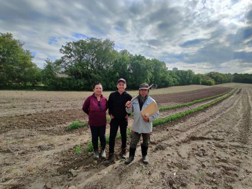 Kia Chang, Houa Lor and Lue Lor standing in a field on their farm