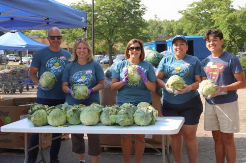 Second Harvest Heartland team poses with lettuce heads at NorthPoint Health & Wellness Center's Fresh Food Fridays distribution