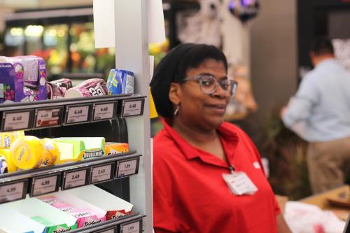 A cashier stands at her grocery checkout counter