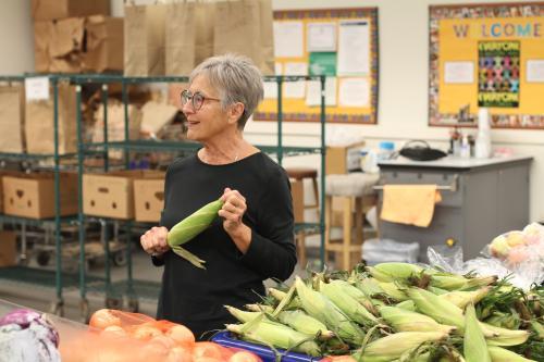 A woman holds an ear of corn in a grocery store