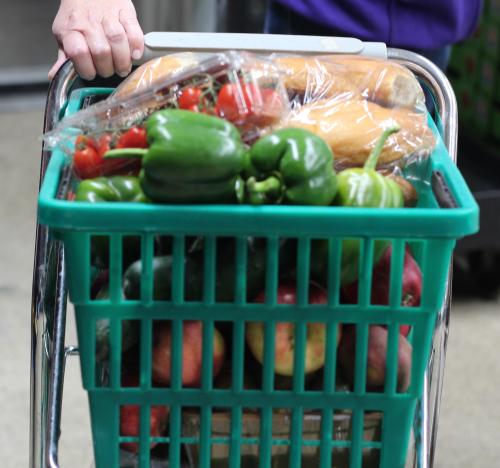 A grocery cart full of fresh produce and bread