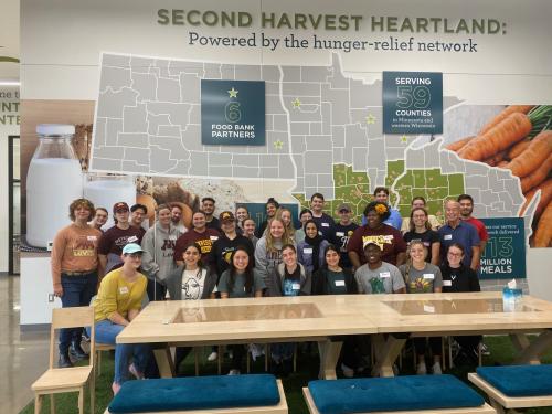 A group of student volunteers pose for a group photo at a food bank.