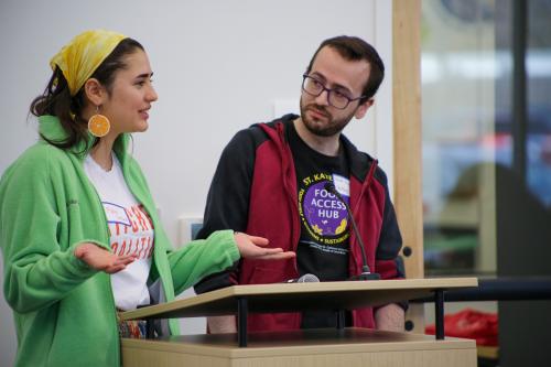 A man and a woman talk behind a lectern