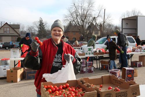 A distribution volunteer holds a vine of tomatoes