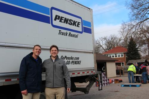 Two drivers stand outside of a Penske truck