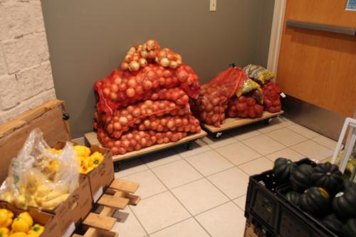 Bags of onions, yellow peppers, and squash in a food shelf