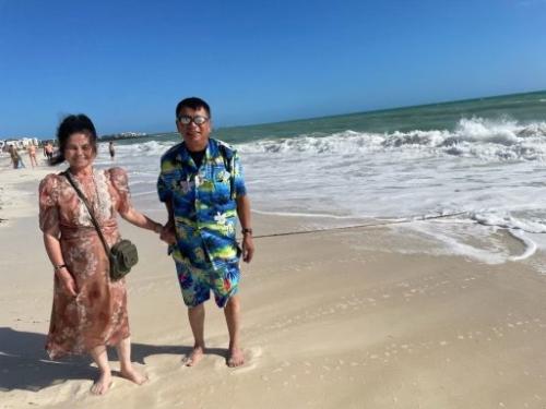 A man and a woman in beach wear on the beach with an ocean behind them