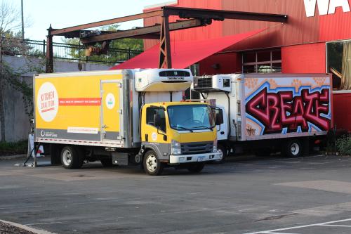 A Kitchen Coalition truck and a Create Catering truck parked outside of Create Catering