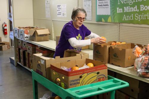 Lorri packing boxes Lorri, wearing a purple CEAP shirt, packs produce boxes