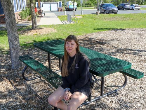 A woman sits outside on a park bench