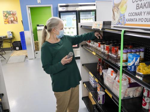 A shopper picks out spices at a food shelf