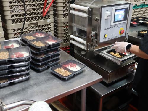 Workers prepare and seal frozen meals