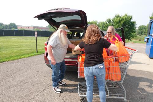 Three people loading groceries from a cart into the back of a car