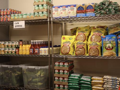 Metal shelves with condiments, fresh produce, cereal and beans