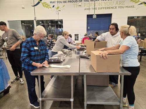 Volunteers labeling and packing bags of cereal in boxes