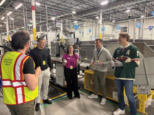 A group of people wearing gloves in a warehouse, laughing and smiling