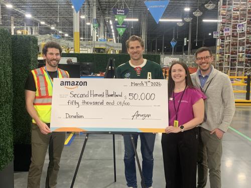 Four people posing with a giant check for $50k