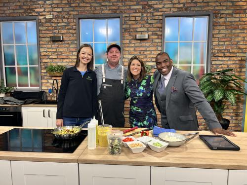 Four people posing in an on-camera kitchen at a news station