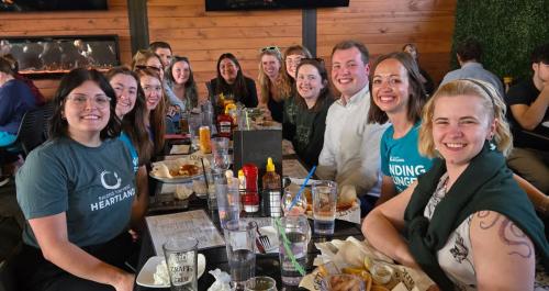 A smiling group at a long table full of dishes at a restaurants 