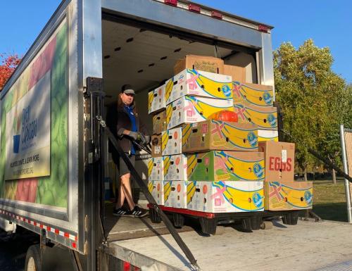 A person in the back of a box truck moving a pallet of food